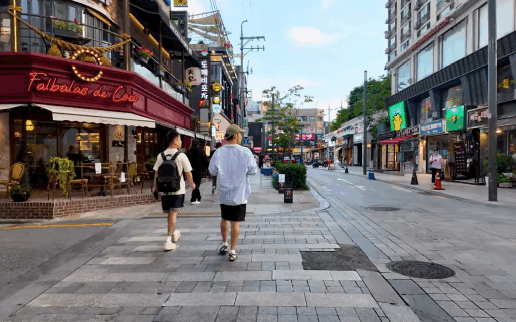 夕方の狎鴎亭ロデオ通りを歩く人々とカフェの並ぶ風景。落ち着いた雰囲気の中、おしゃれなレストランやショップが立ち並ぶ通りの様子。