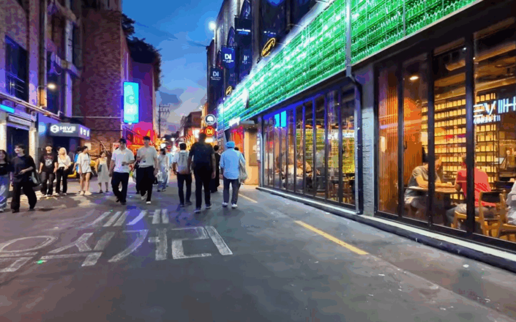 夜の梨泰院クラブ通りを歩く人々の様子。ネオンが光る飲食店やバーが並び、にぎやかな雰囲気に包まれた人気エリアの風景。