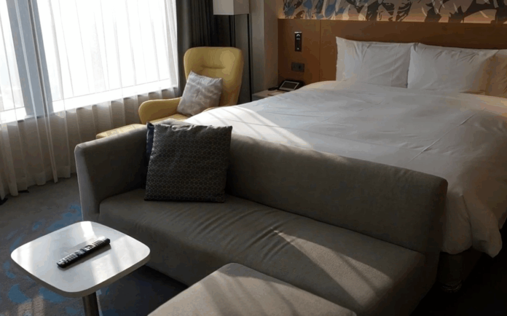 ソウル龍山区ノボテルスイーツアンバサダーホテルのジュニアスイートルーム内装 モダンなホワイト・グレーインテリア イエローアームチェア グレーソファ 大型ダブルベッド完備 ビジネス・カップル向けラグジュアリースイート K-POP推し活に最適