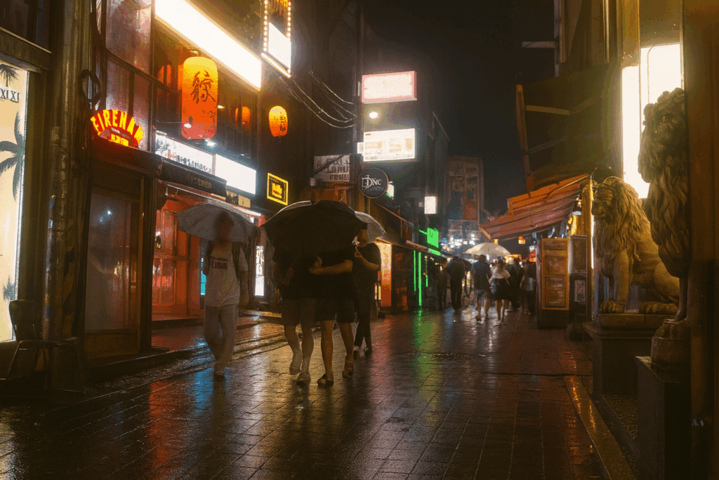 雨のソウルナイトストリートを歩く人々と光るネオン。若者が集まる人気エリアの夜景で、ソウル旅行の雰囲気が伝わるシーン。