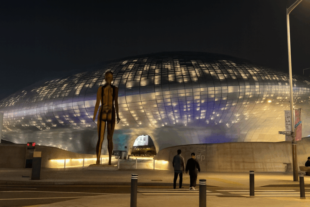 夜の東大門デザインプラザ（DDP）のライトアップされた外観。未来的な建築デザインが印象的で、ソウル旅行の人気夜景スポット。